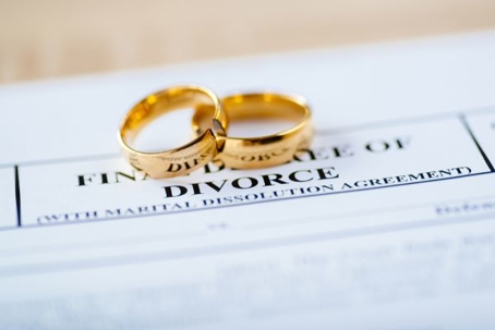 Two golden wedding rings rest on top of divorce papers.