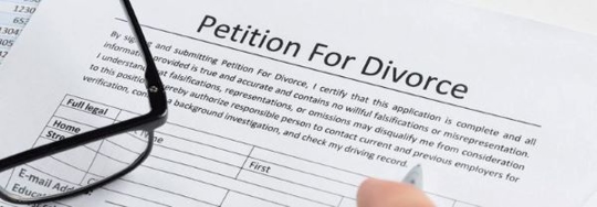 An extreme close up displays a hand completing a Petition For Divorce form.