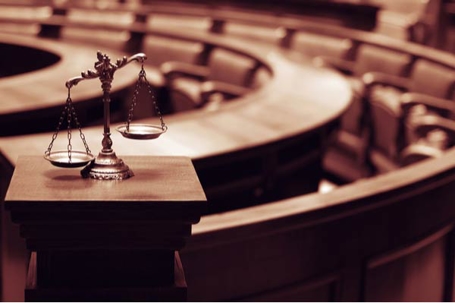 Scales of justice rest on a pedestal in a courtroom.