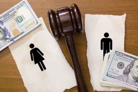 Illustrative stock photo of a divorce settlement including a gavel, torn images of a man and woman, and stacks of $100 bills.