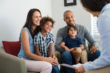 A cheerful family of four sits together during what seems to be a consultation.