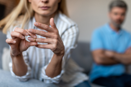 Unhappy middle aged european lady takes off ring, ignoring man during quarrel in living room interior, cropped