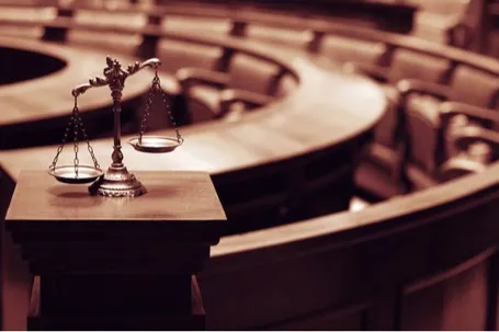 Scales of justice on a pedestal inside a courtroom.