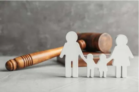 White family figurines standing in front of a judge's gavel and block.
