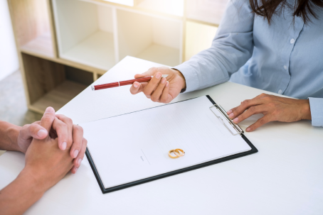 Husband and wife are reading divorce agreement and filing pen to signing decree of divorce (dissolution or cancellation) of marriage filing divorce papers and two golden marry ring