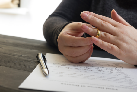 Hands of wife, husband signing decree of divorce, dissolution, canceling marriage, legal separation documents, filing divorce papers or premarital agreement prepared by lawyer. Wedding ring