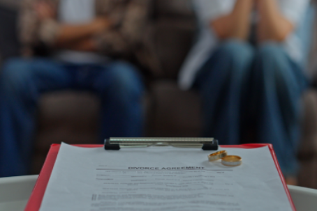 Couple finalizing Divorce Agreement with wedding Rings on Clipboard